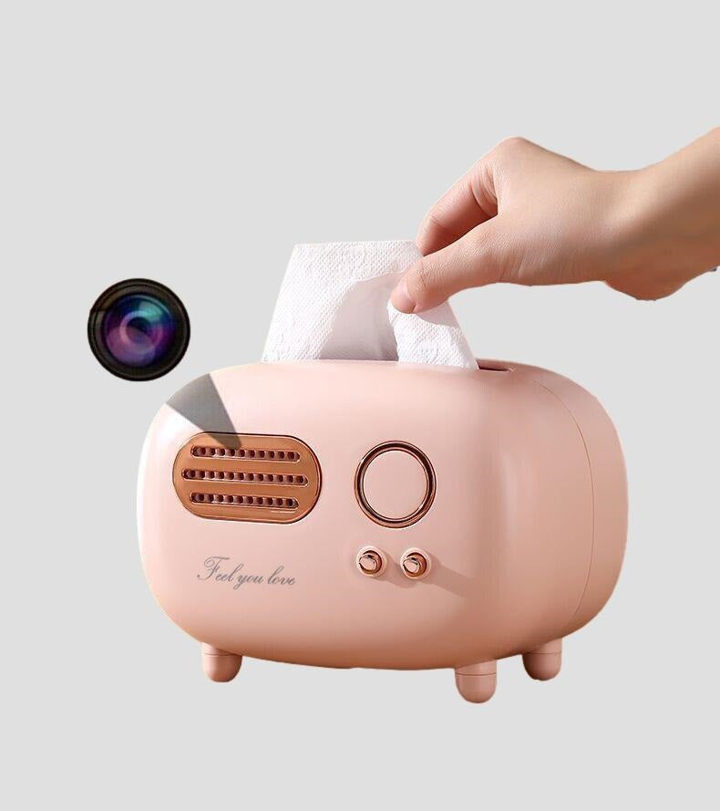 A hand pulling a tissue from a pink toaster-shaped Tissue Box SpyCam dispenser.