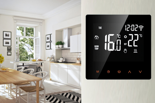 A digital thermostat with an LCD touch screen user interface is shown in a kitchen.