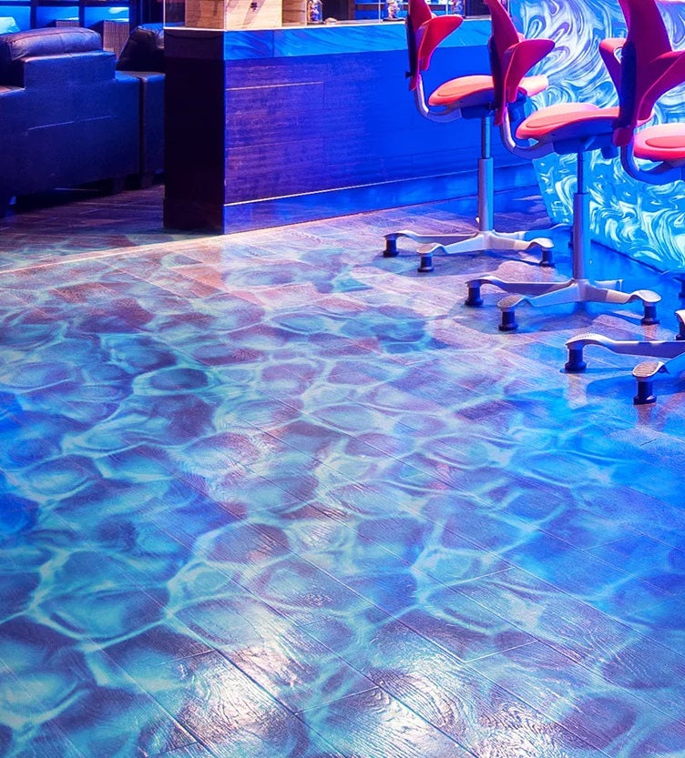 Blue illuminated floor mimicking water waves in a room with modern chairs and blue-toned decorative elements, enhanced by a Water Ripple Projector.