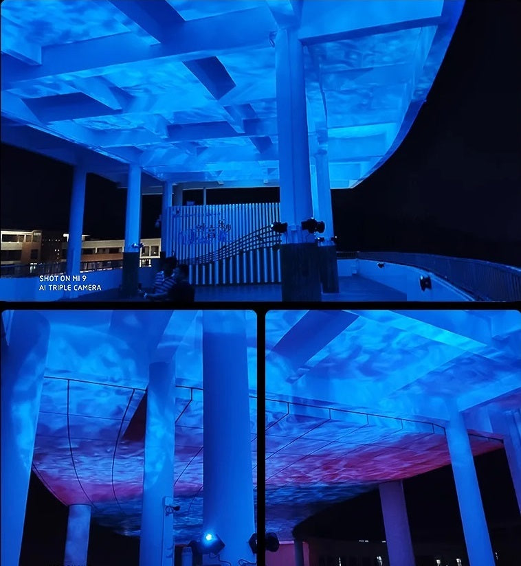 Illuminated blue architectural structure with ambient lighting and ceiling panels, captured at night, displaying a vibrant blue glow.