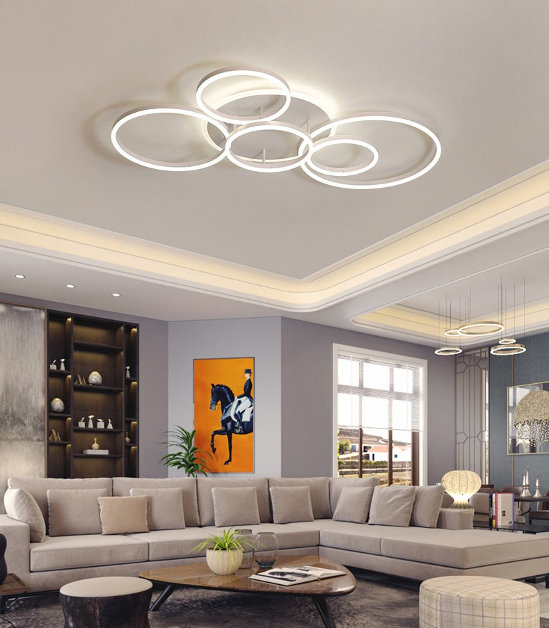 A modern living room with a circle ceiling lamp which emits cool white light.