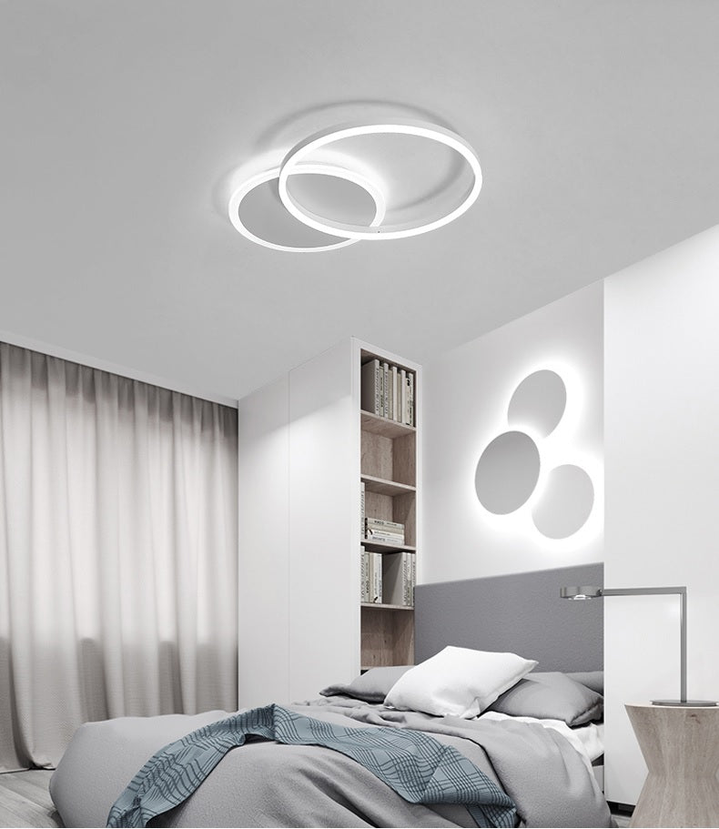 A modern bedroom with a brushed nickel ceiling light featuring interlocking rings.