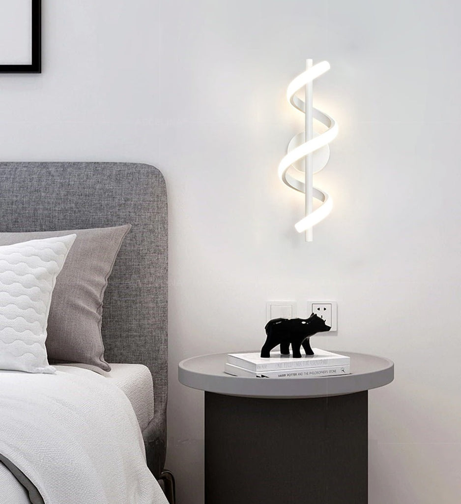 A bed with a Spiral Wall Lamp and a teddy bear.