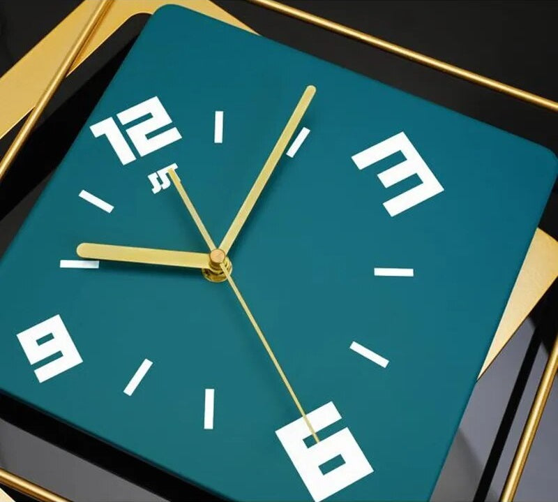 A minimalist design clock with flair is sitting on a table next to a gold frame.