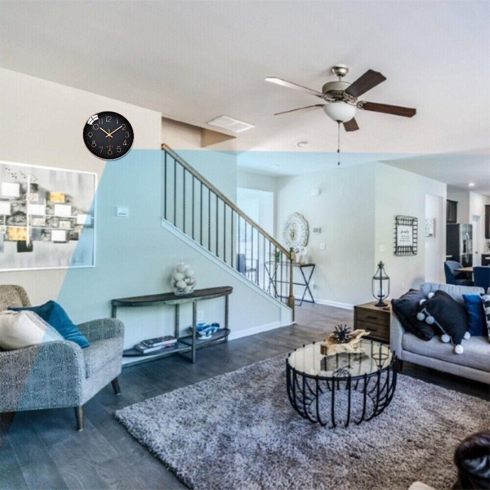 A modern living room interior with a staircase, ceiling fan, and a black Wall Clock Spy Cam on the wall featuring HD 1080P recording.