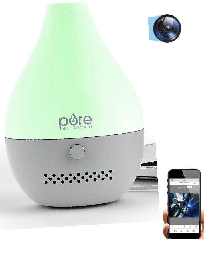 An ultrasonic essential oil diffuser with a color-changing led light, featuring a hidden WiFi camera technology for home surveillance, next to a smartphone with a camera interface open on its screen.
