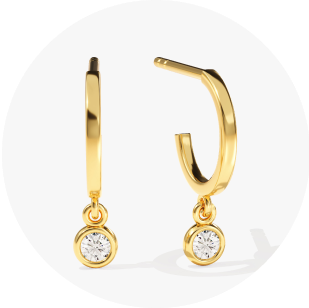 Eternate's yellow gold huggies with bezel set diamond in front of a white background