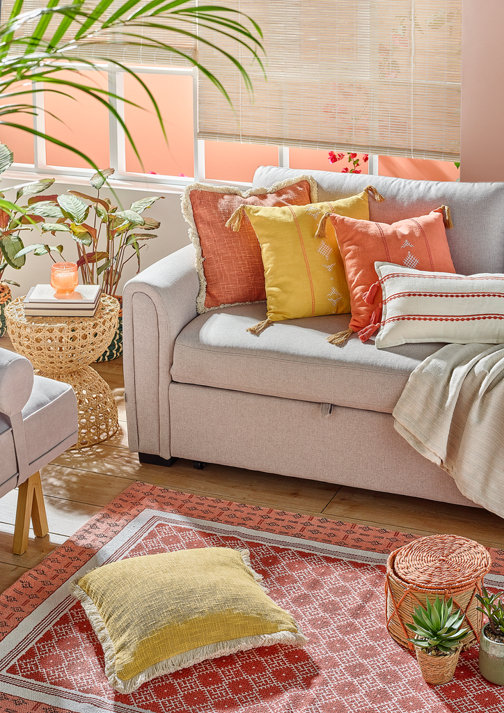 Sofá cinzento decorado com almofadas rosa e amarelo da coleção Warm Boho.