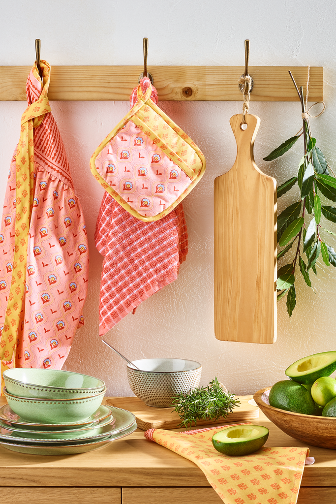 Móvel de Cozinha decorado com pratos verdes e têxteis da coleção Warm Boho - aventais, luvas de forno e panos.