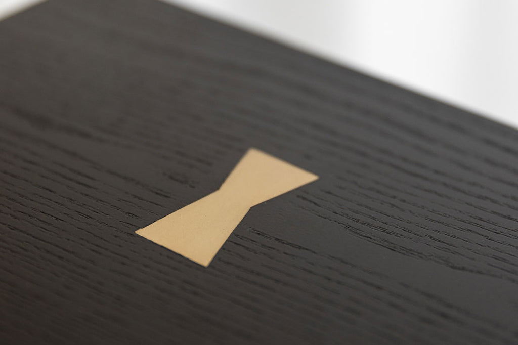 Close-up image of a brass bow-tie detail inlayed into sideboard top