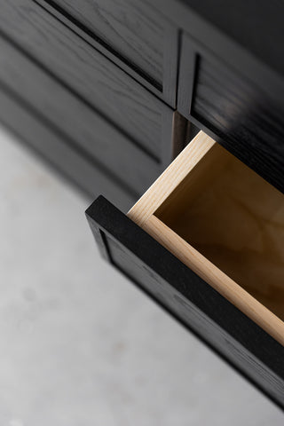 Close-up image of the top vie of the open sideboard drawer. The drawer inside is light Ash wood, and dark black lacquer on the outside