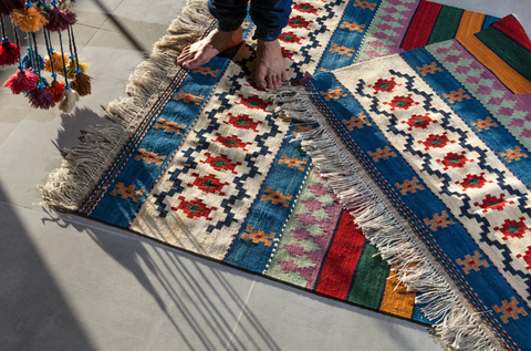 A woman standing on tufted rugs.