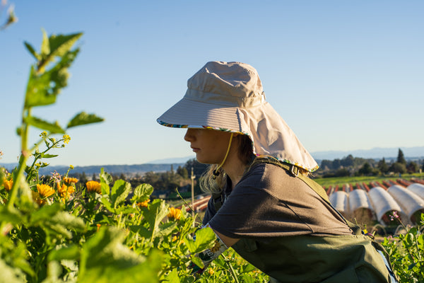 A gardener in the field wearing a hat to protect her skin.
