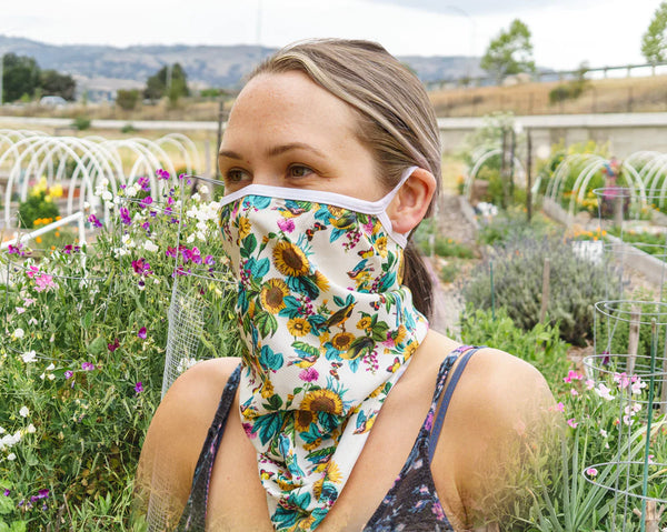 Woman wearing neck gaiter in a field to protect face.