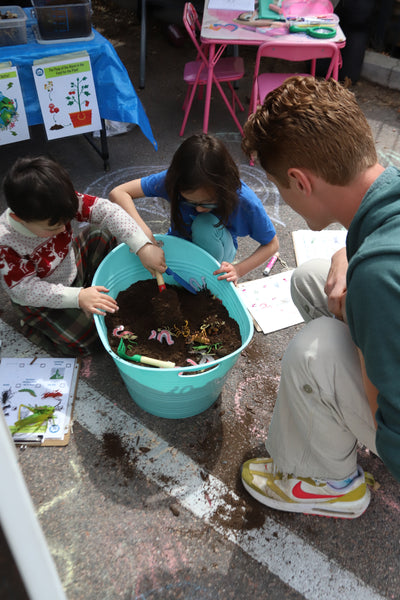 A group of kids gathered around potting soil. 