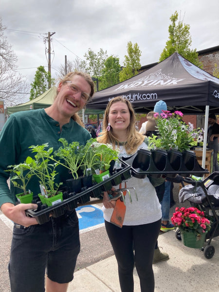 A couple holding all the plants they just purchased.