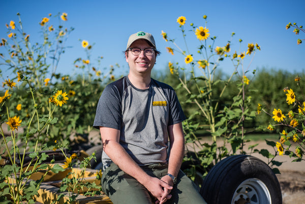 Miles sits in front of the native flowers covered in pollinators.