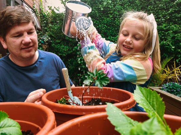 Father and daughter water plants in pots. 