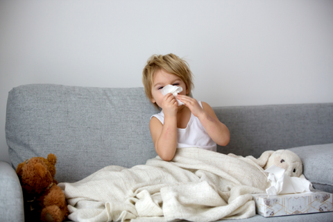 Child blowing his nose on the couch