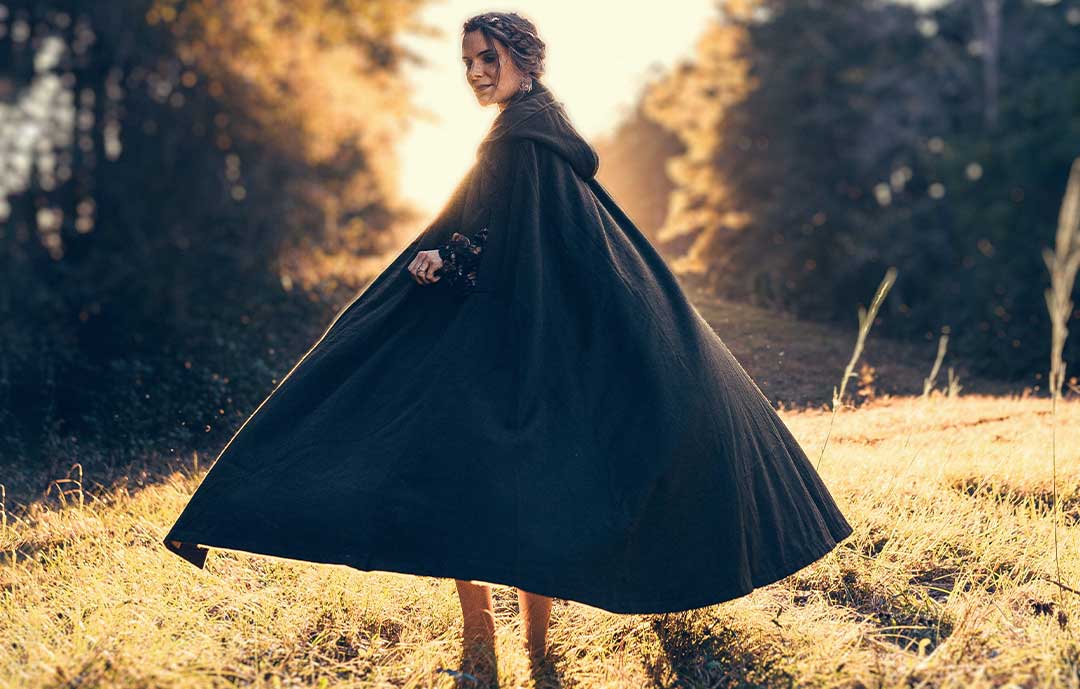 Women wearing a cloak or cape in a field