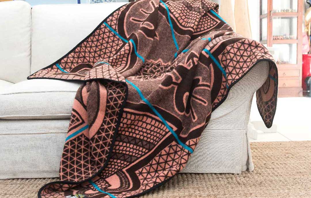 A Basotho heritage wool blanket from Africa draped over a white couch