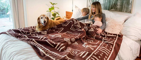 A women with her kids sleeping on bed in the Thula Tula Blanket