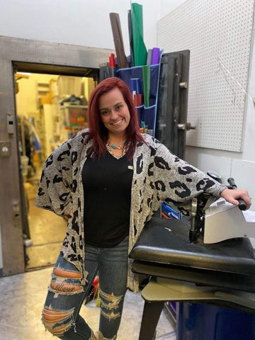 Show owner Emily standing in shop area. Behind you can see parts of the shop including the vault door and press