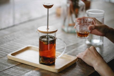 A person's hands drinking a cup of mushroom tea.