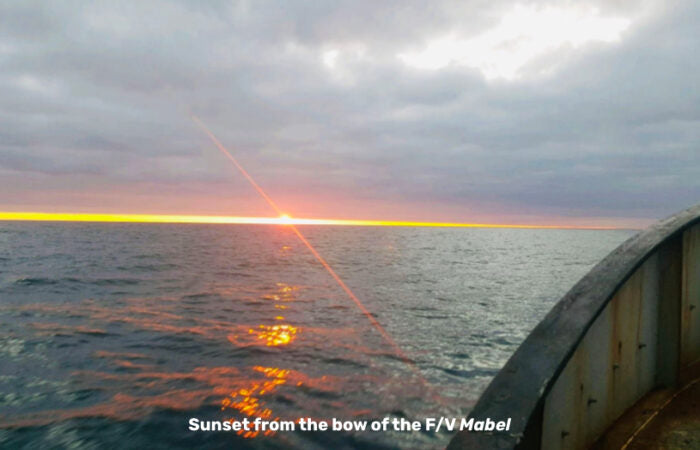 A sunset viewed from the bow of a fishing vessel