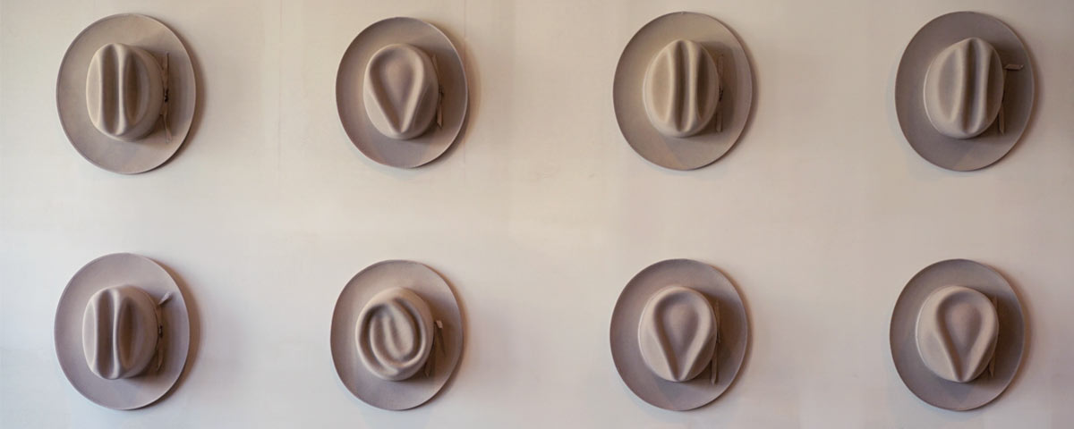 Chapeaux Fedora avec formes de couronnes diveres accrochés au mur