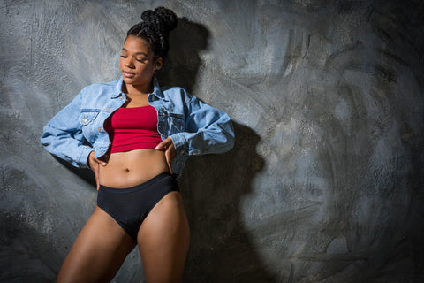 Model wears black seamless Heralogie period underwear while posing against a backdrop. The period panties look like regular, thin, comfortable underwear.