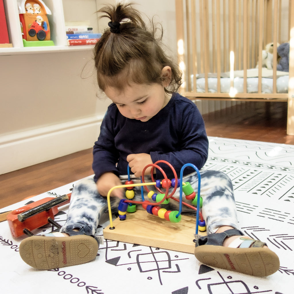 Baby on play mat playing with development toy