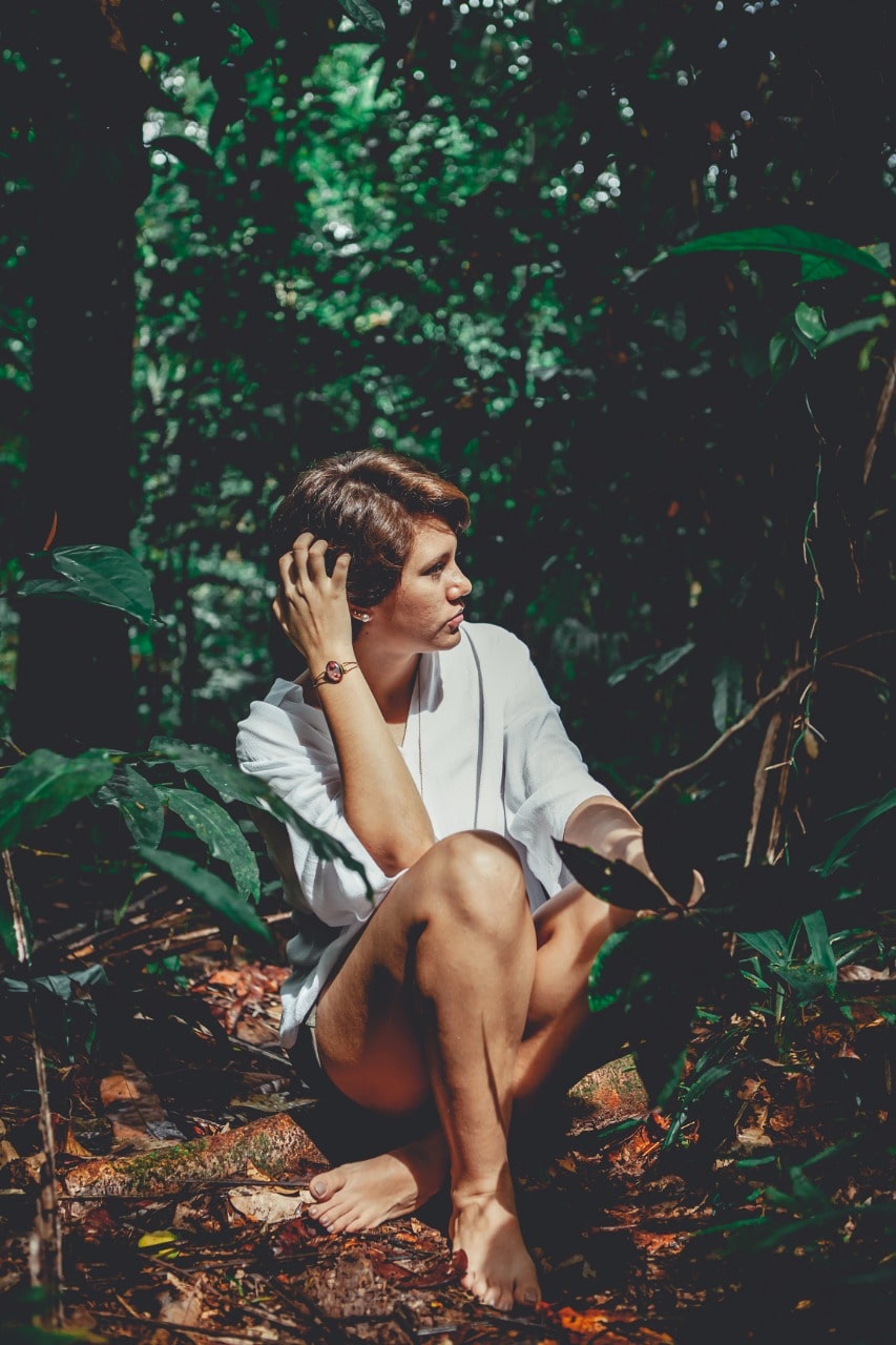 Foto da artista Hadna Abreu sentada na floresta