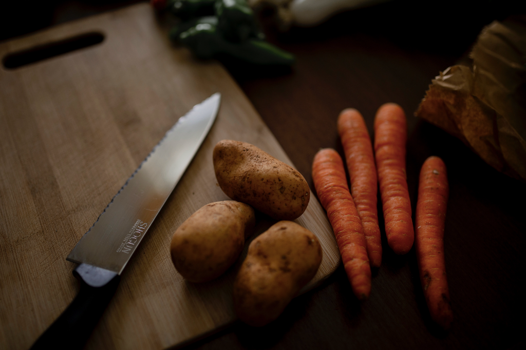 A cutting board and knife with vegetables