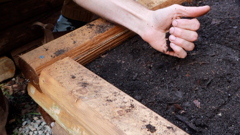 Worm castings being sprinkled into a raised bed