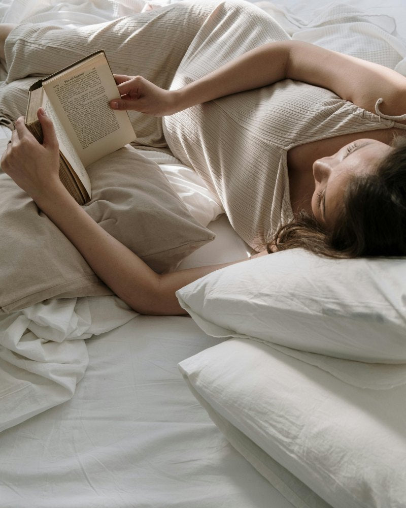 Woman lying in bed reading a book.