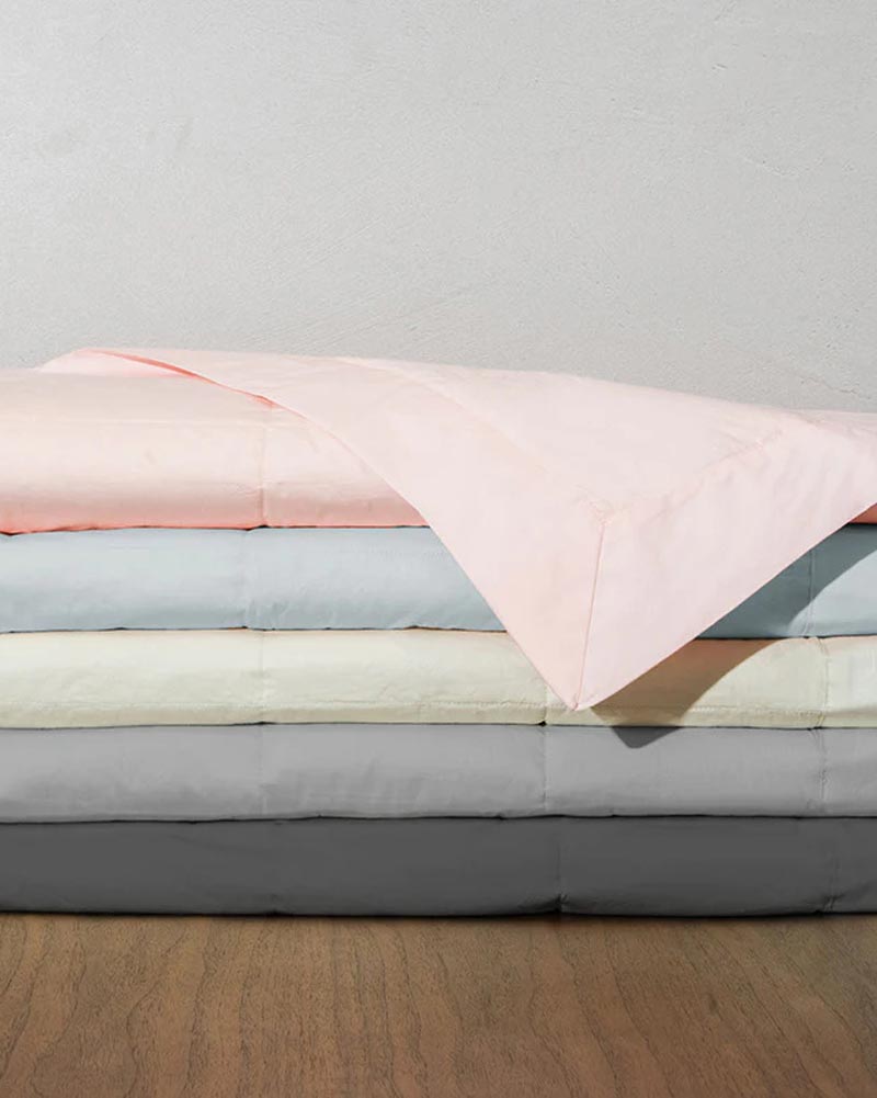 Stack of five folded-down blankets in pink, blue, green, gray, and charcoal