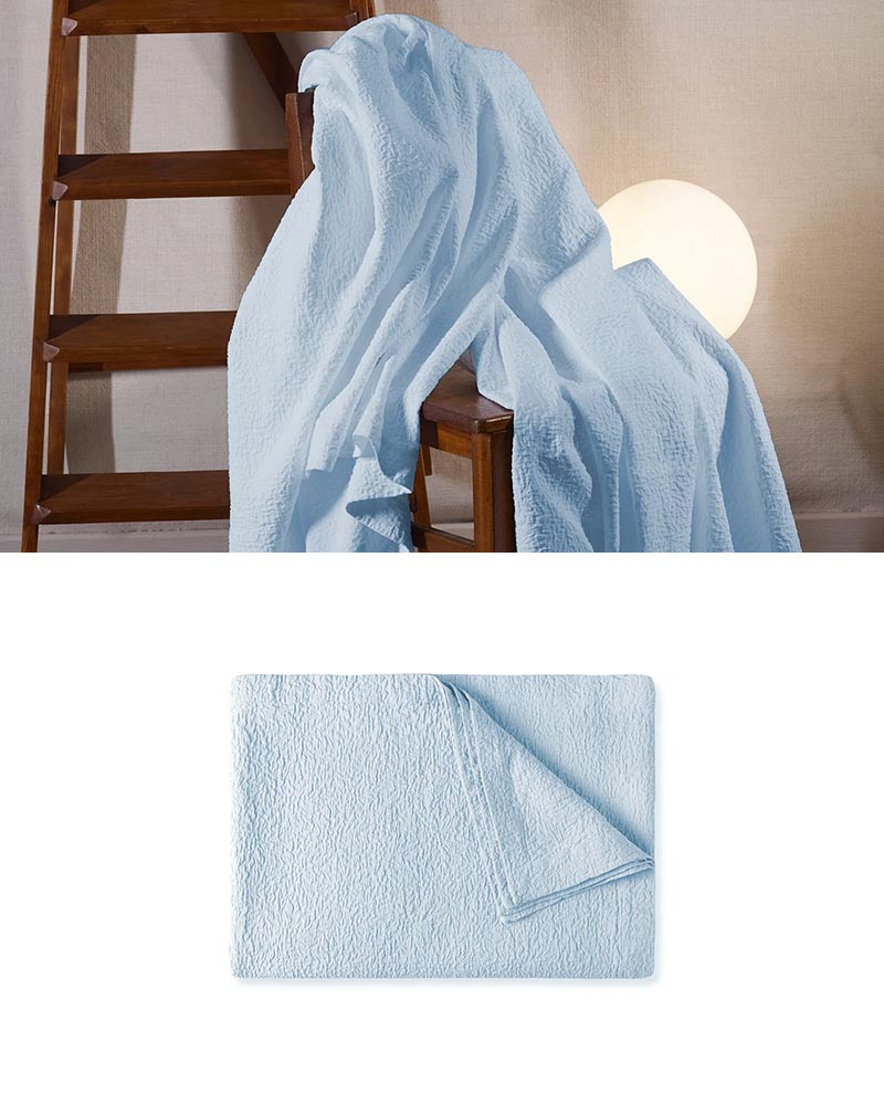 blue coverlet on a chair with a wooden ladder behind and a lamp turned on