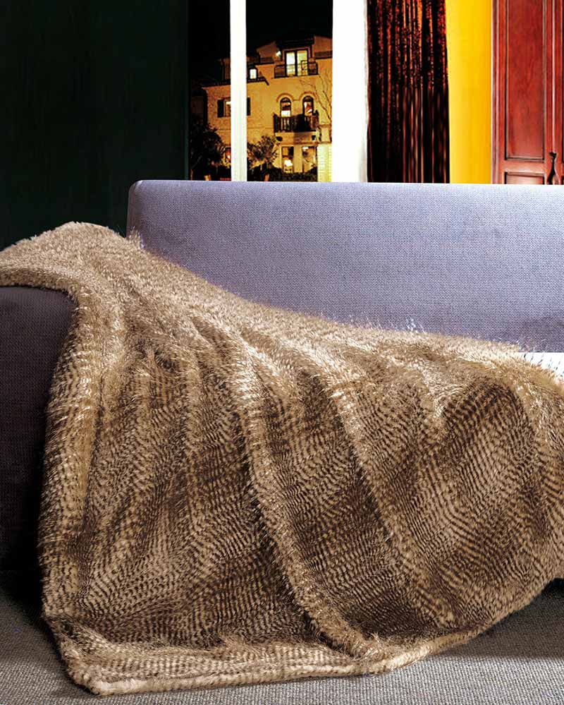 faux fur throw blanket in shades of brown spread out on a sofa with the night outside the window