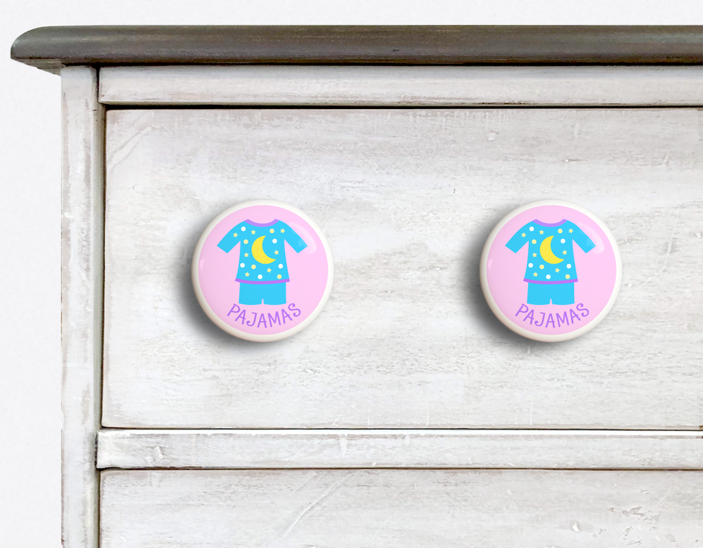 2 Ceramic drawer knobs on a dresser, girls pajamas on a pink ground with the word Jammies written below