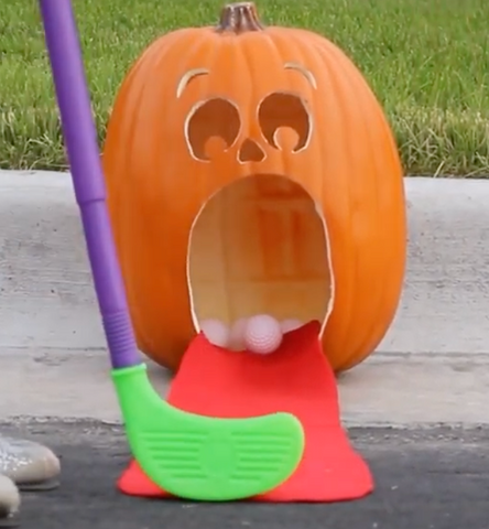 A carved pumpkin that has been turned into a putt putt game for kids