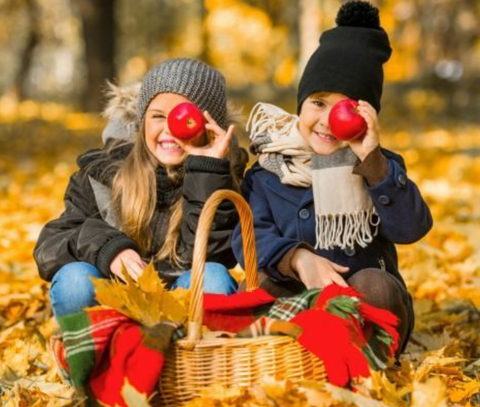 Image of children playing in fall leaves with apples 