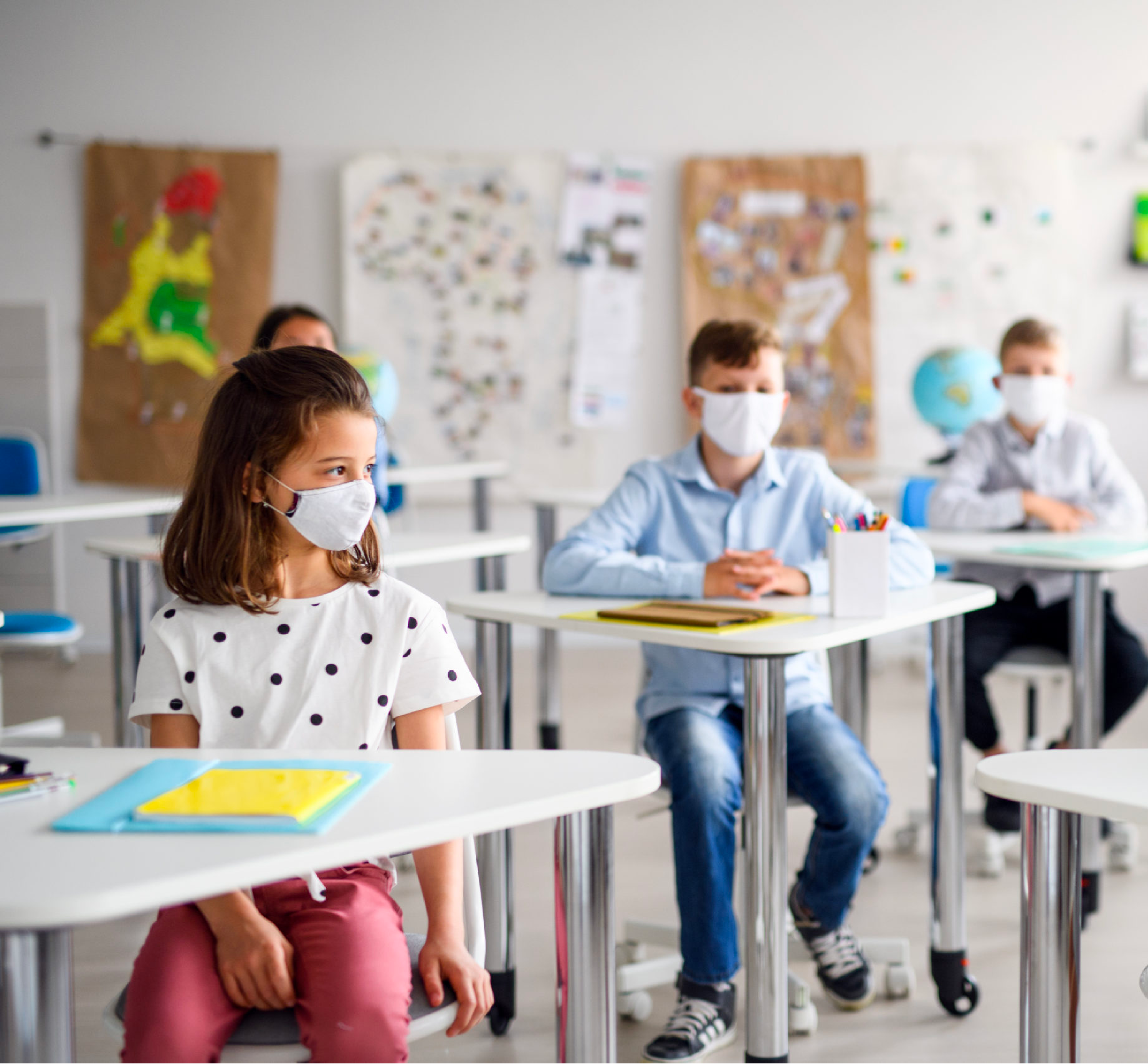 Children in masks in a well lit classroom