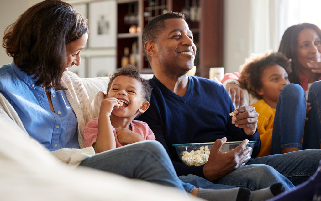 family sitting on their couch watching a movie together