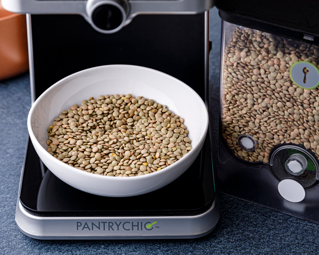 Dispensing dried green lentils into a bowl to add to the pot of chickpeas