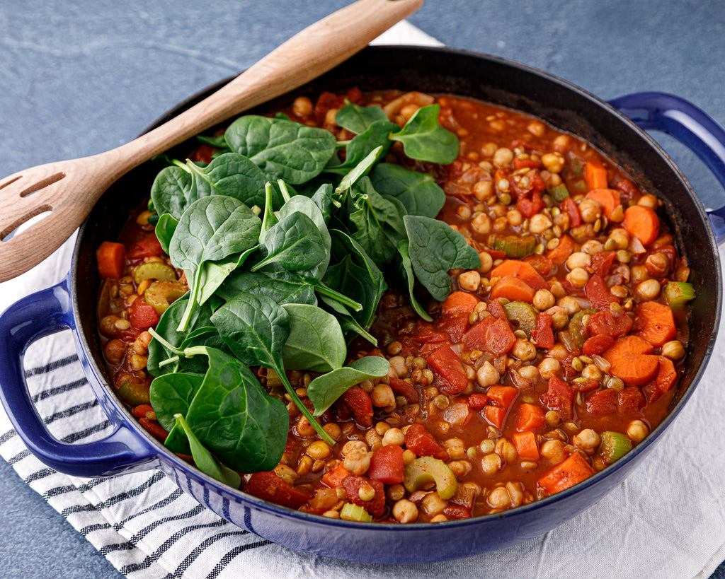 The nearly finished stew with fresh spinach being added