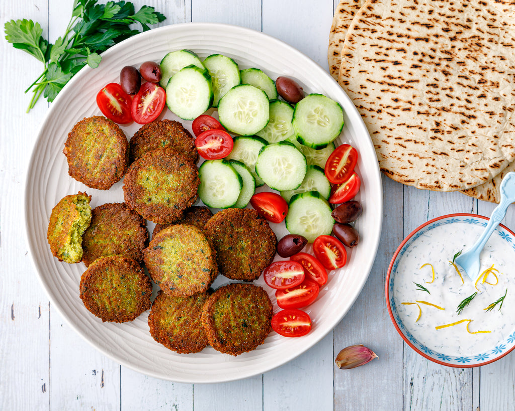 Homemade falafel on a platter with cucumbers, tomatoes, and Kalamata olives