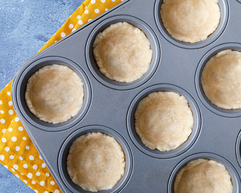 Pressing the cookie cup crust into muffin cups