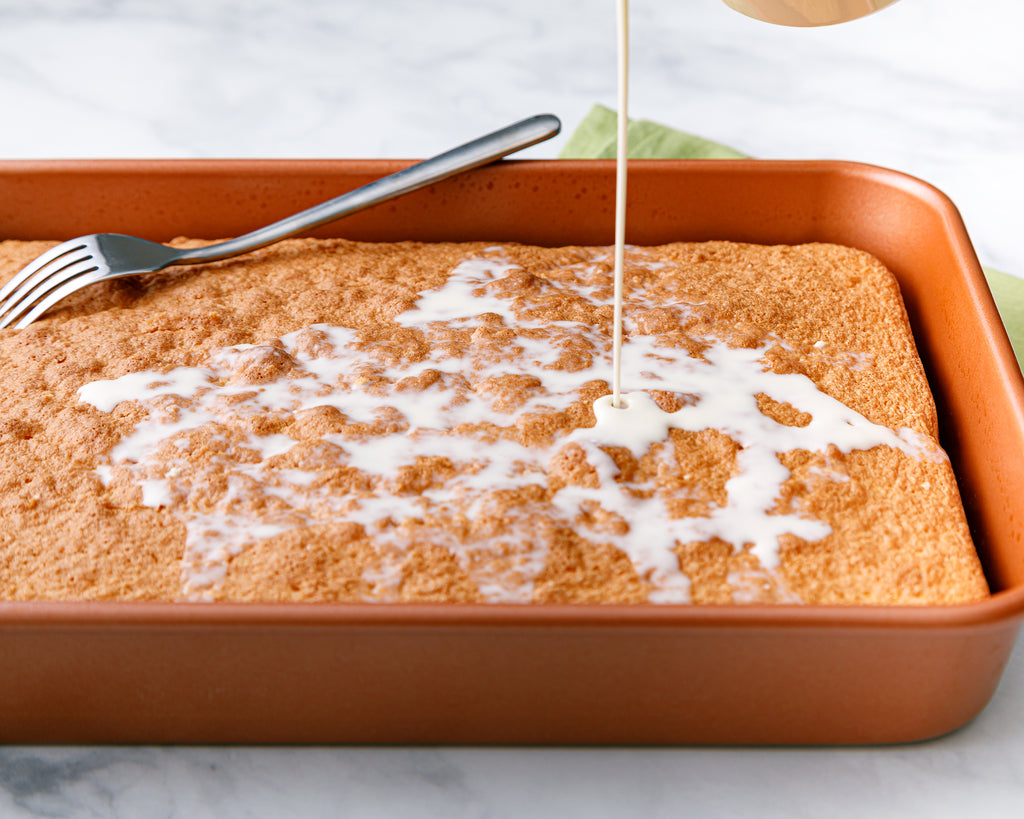 Pouring the three milks over the cake to soak