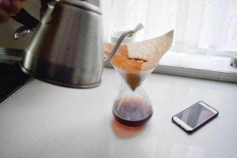 Kettle pouring hot water into a Chemex to make coffee